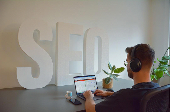 Person works on laptop with "SEO" sign in background.