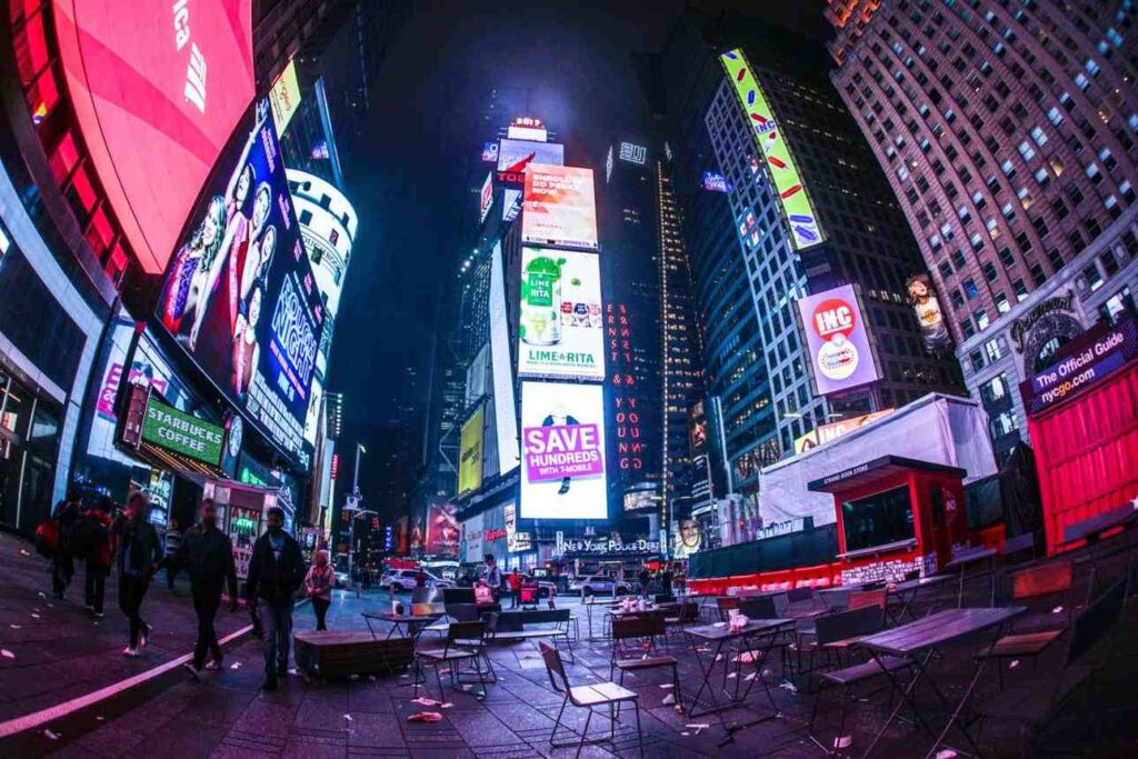 Times Square at night with bright billboards and empty tables, New York City Weekend Trip